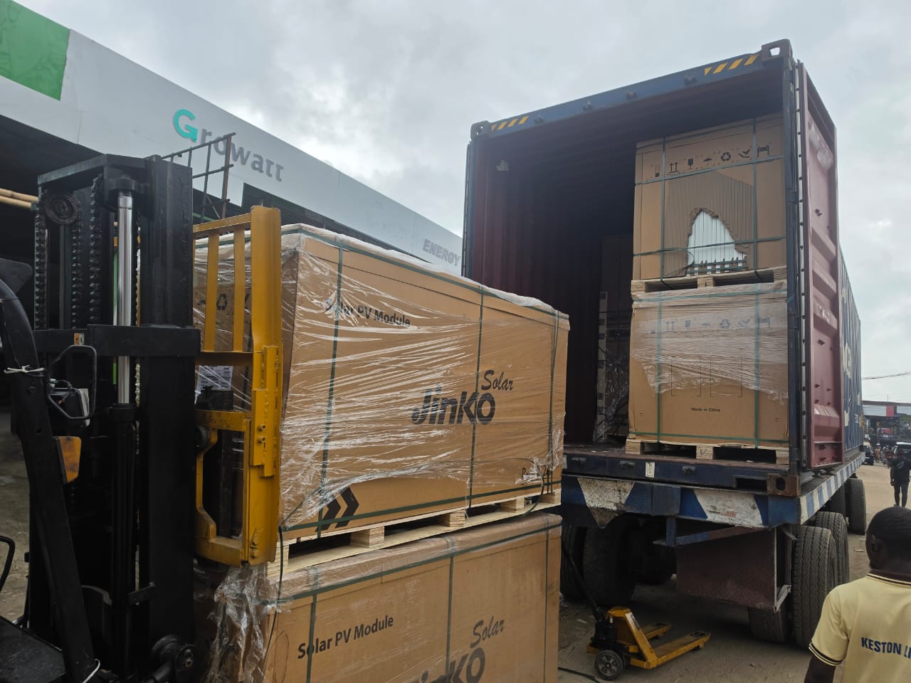 Forklift offloading crated solar PV modules from a container truck