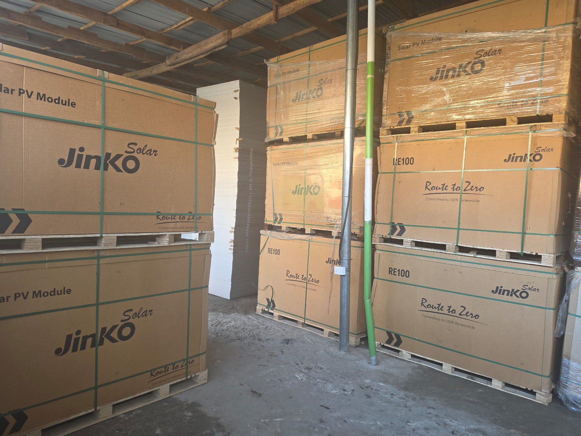 Stacked pallets of boxed solar PV modules stored in a warehouse
